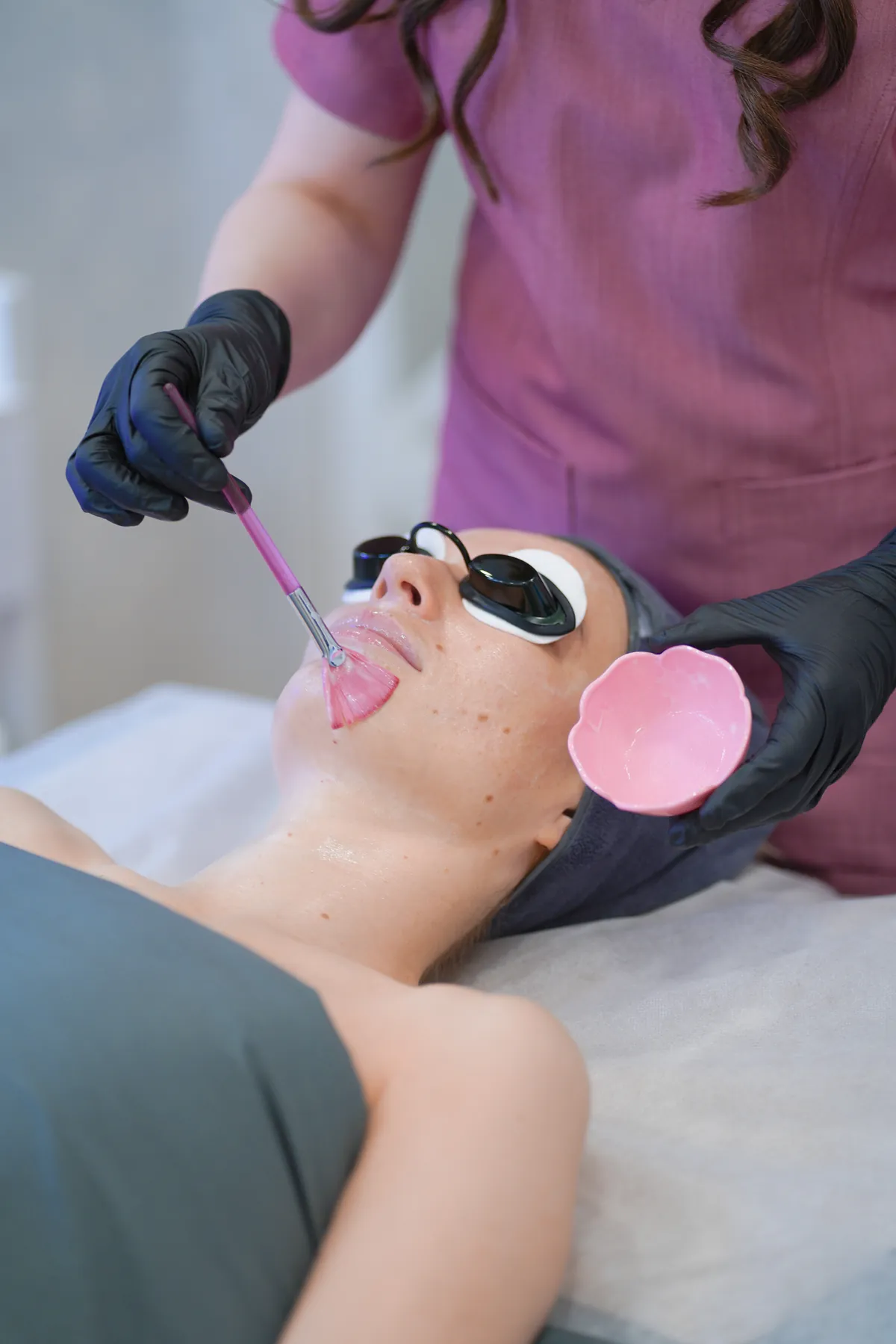 Licensed esthetician applying a customized chemical peel solution with a fan brush at SI Glam Glow in Staten Island, New York