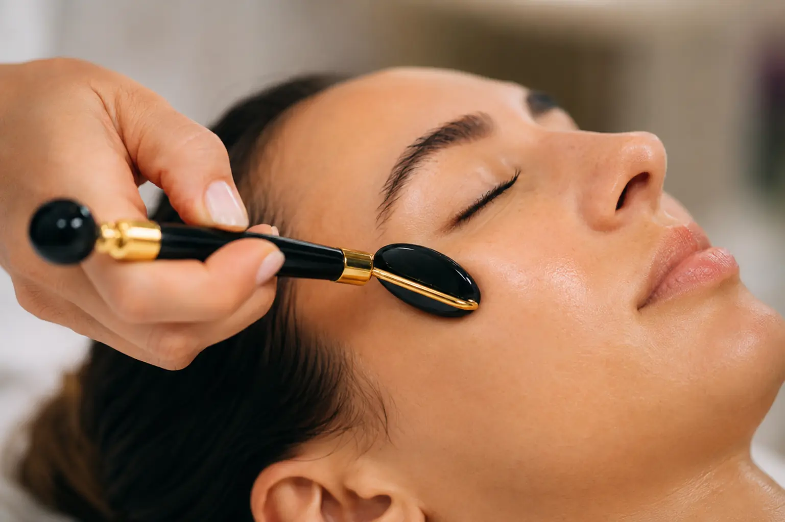 Licensed esthetician using a gua sha facial tool during a holistic facial treatment at SI Glam Glow in Staten Island