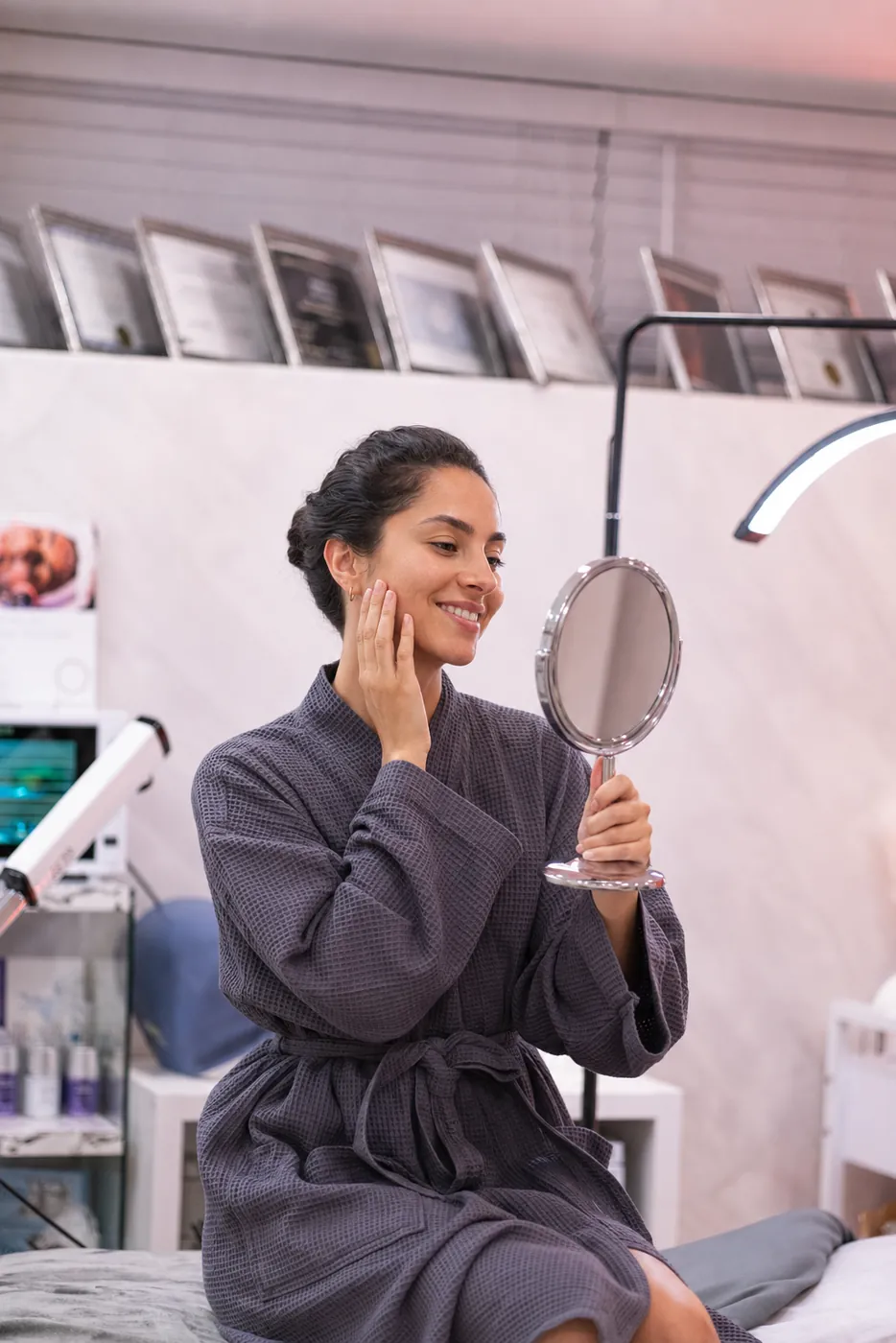 Client admiring her glowing results after a Microcurrent Lifting Facial at SI Glam Glow