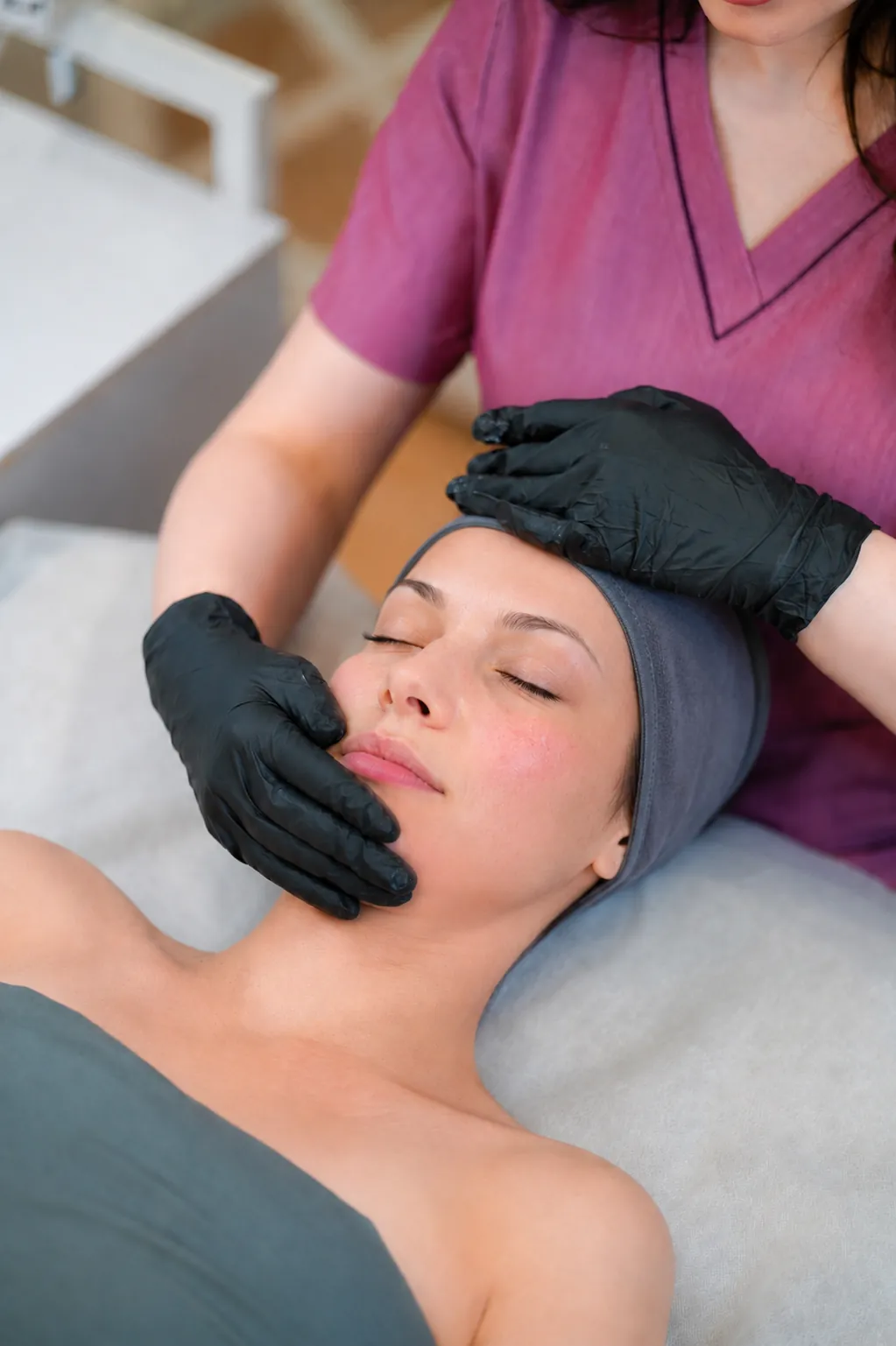 Esthetician gently cupping a client's face during a Rosacea Rescue Facial at SI Glam Glow