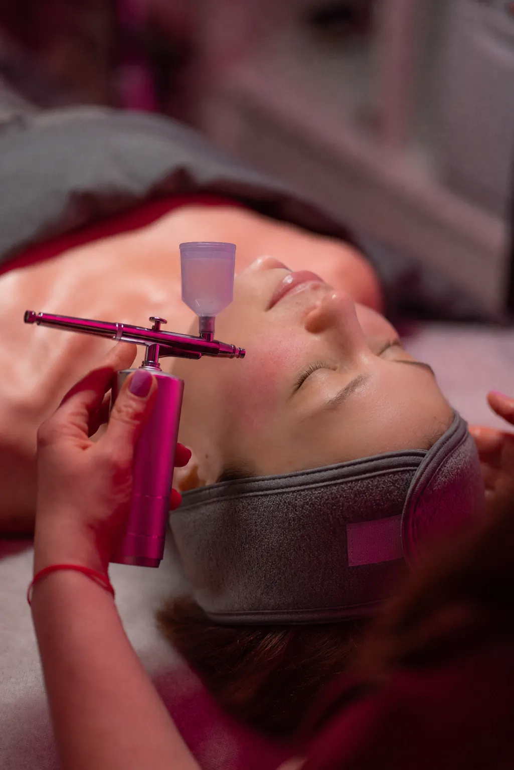 Licensed esthetician performing an oxygen infusion spray during a Rosacea Rescue Facial at SI Glam Glow