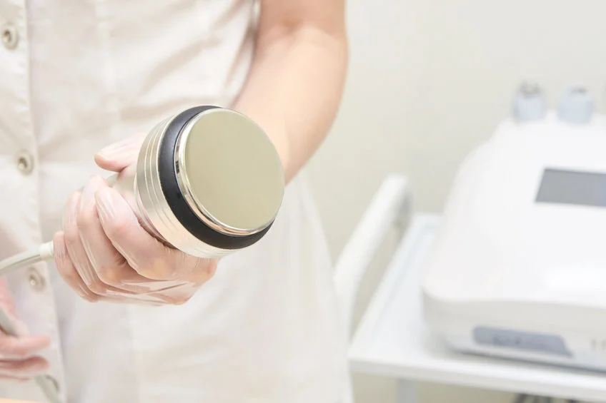 Esthetician preparing the Ultrasonic Cavitation handpiece before a body contouring session at SI Glam Glow