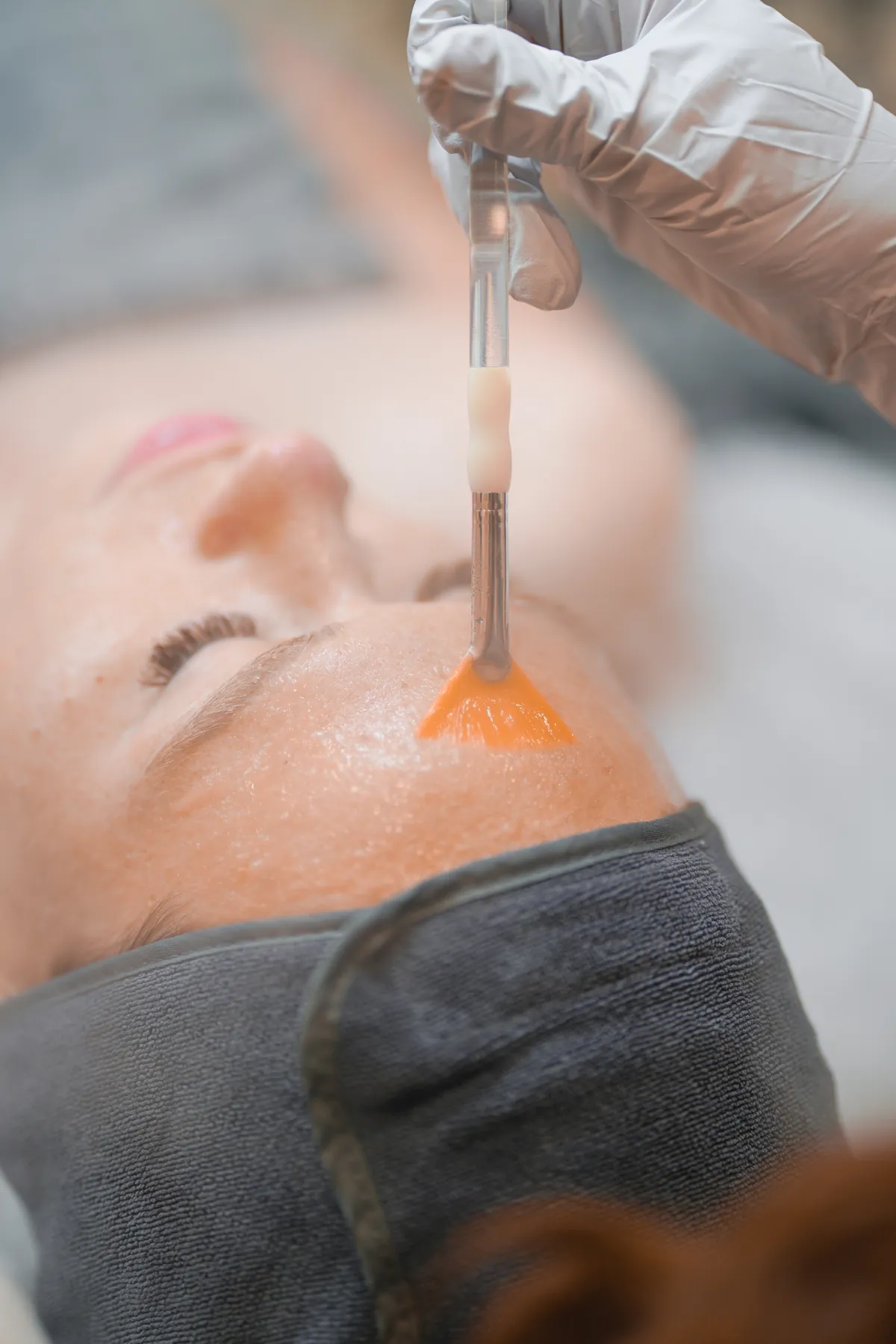 Licensed esthetician applying a customized chemical peel solution with a fan brush at SI Glam Glow