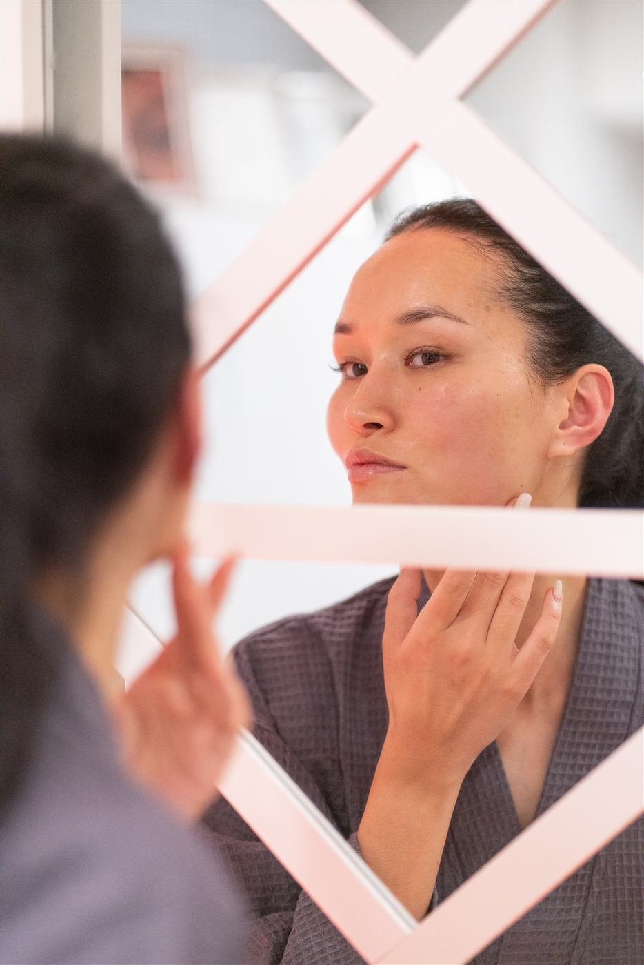 Client admiring smooth, glowing skin after a Dermaplaning Facial