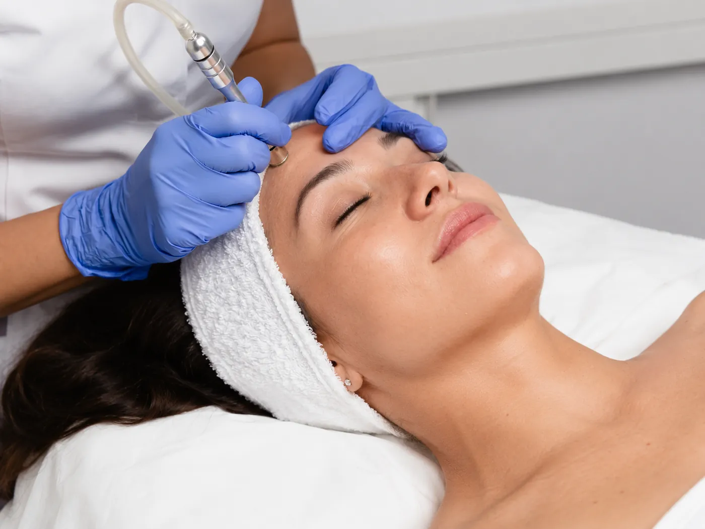 Licensed esthetician performing a microdermabrasion treatment on a client's forehead at SI Glam Glow in Staten Island