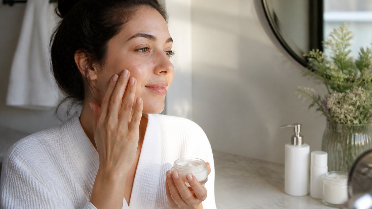 Person applying moisturizer to glowing skin to learn how to maintain a glow after professional facials